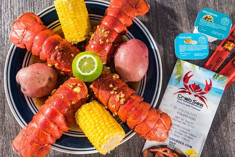 Crab boil platter with lobster tails, potatoes, corn, and seafood seasoning packets