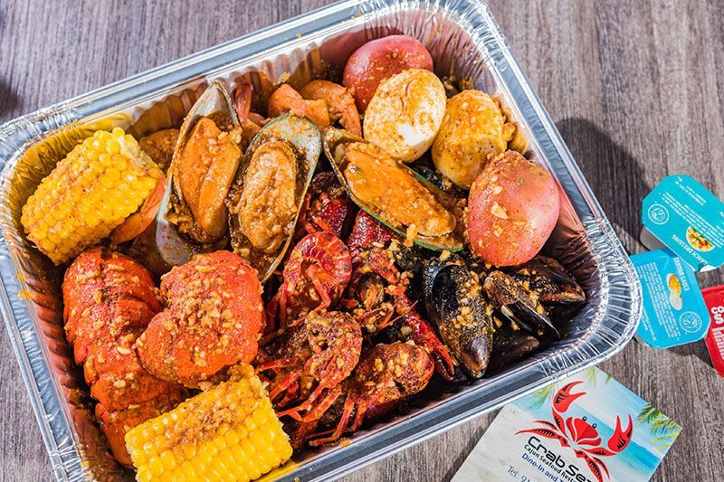 Assorted seafood boil with corn, potatoes, and crab in a foil tray
