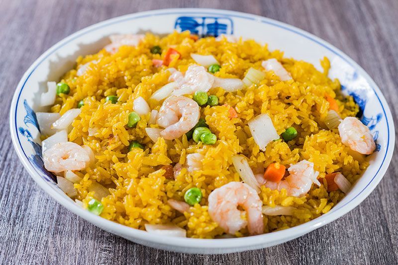 Shrimp fried rice in a white bowl with peas, carrots, and diced vegetables