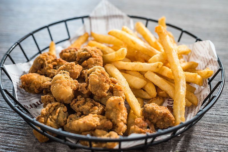 Basket of fried chicken bites and French fries on a table