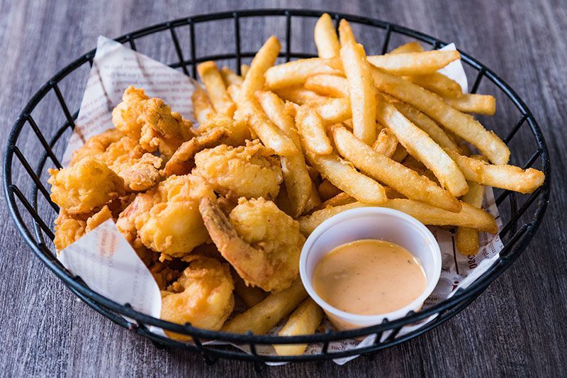 Fried chicken bites and French fries in a basket with dipping sauce