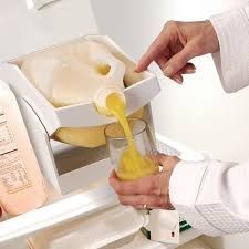 Image of the Pour Thing drink dispenser holding a jug of orange juice being poured into a cup.