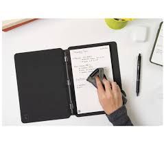 A person erasing notes from a reusable notebook with a small eraser, on a white desk.