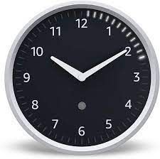 Clock with black face, white hands, white numerals.  Lights illuminate around the clock face.