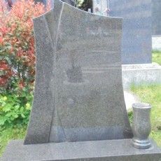 Ein Grabstein mit einer Vase darauf auf einem Friedhof.