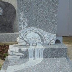Ein Grabstein mit einem darin eingemeißelten Wasserfall und einer Brücke.