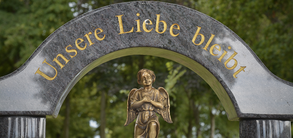 A statue of an angel is under a sign that says unsere liebe bleibt