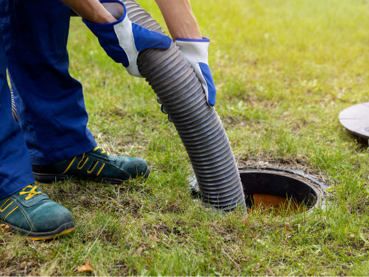 A person wearing yellow gloves is opening a septic tank.