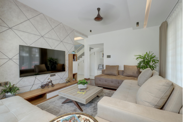 A living room with a couch, table and chairs and a kitchen in the background.