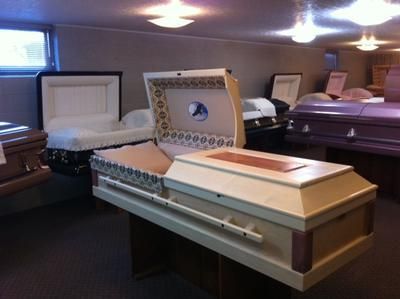Funeral home viewing room with open casket and surrounding caskets on display