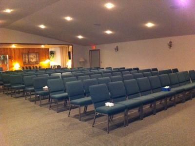 Empty church sanctuary with rows of blue chairs and soft ceiling lights