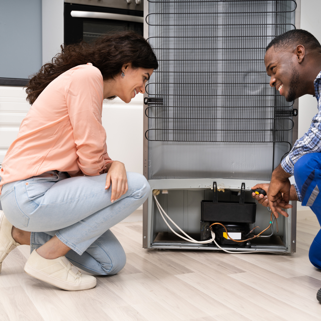 Un hombre y una mujer están trabajando en un refrigerador.