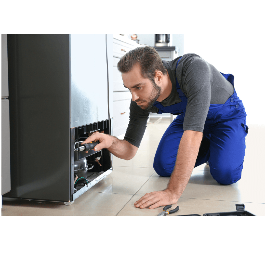 Un hombre está arrodillado en el suelo arreglando un refrigerador.