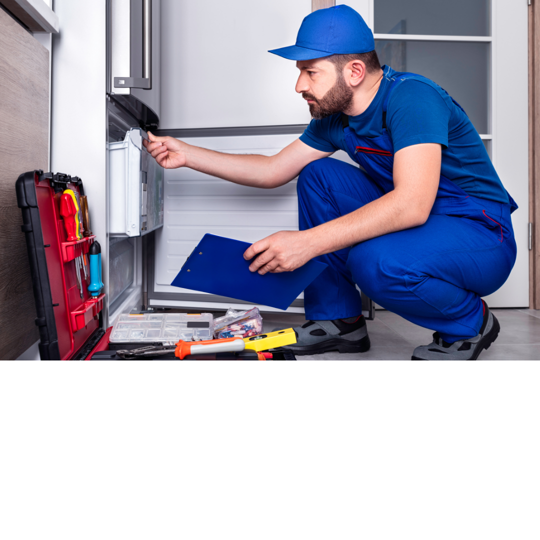 Un hombre con un mono azul está trabajando en un refrigerador.