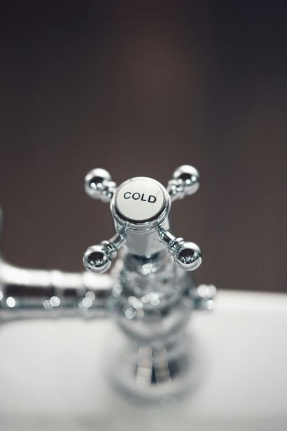 A close-up, top-down view of a shiny chrome faucet handle with the word 