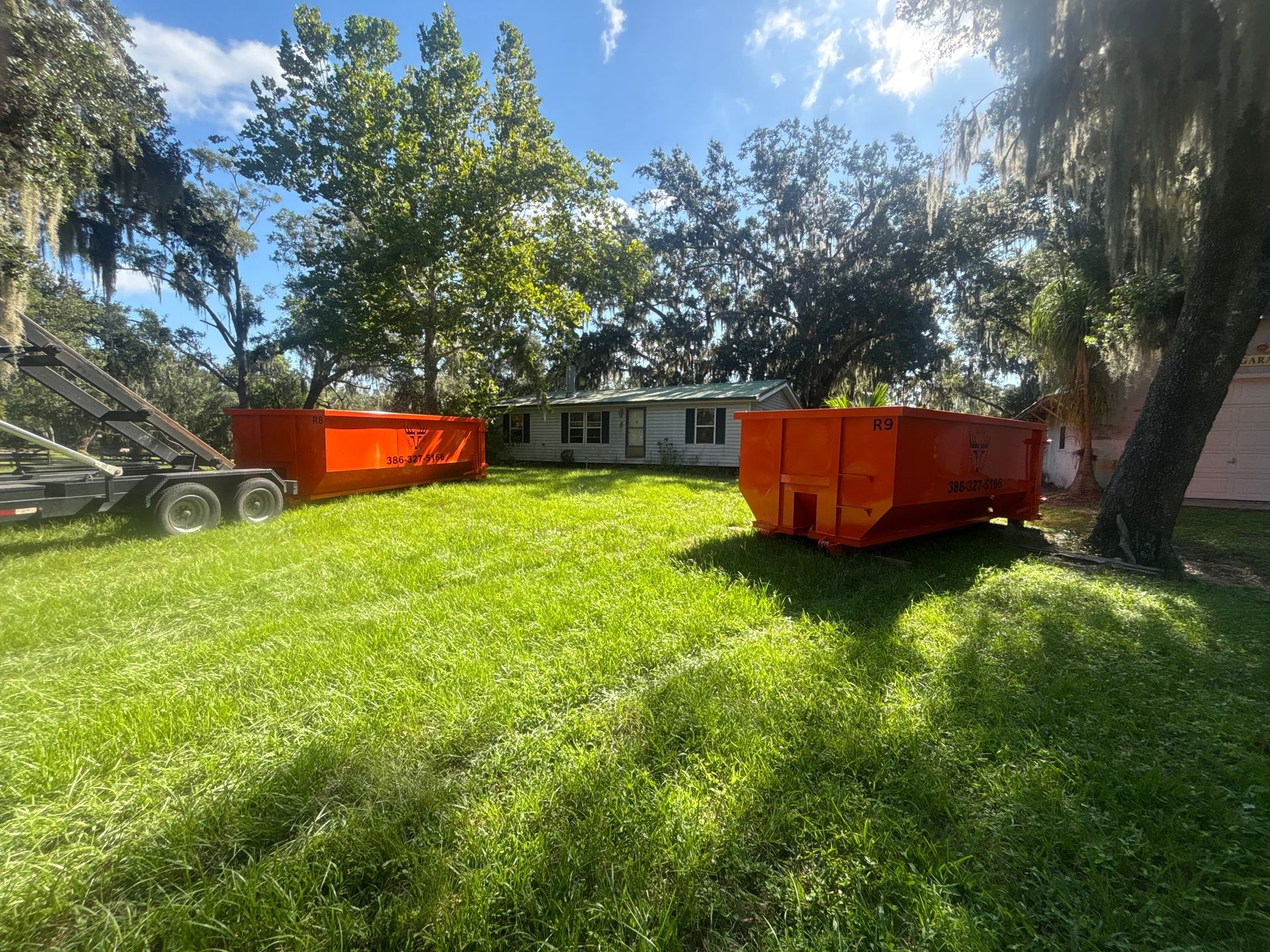 Two orange Volusia Trash Masters 20-yard roll-off dumpsters delivered to a property in Volusia County Florida