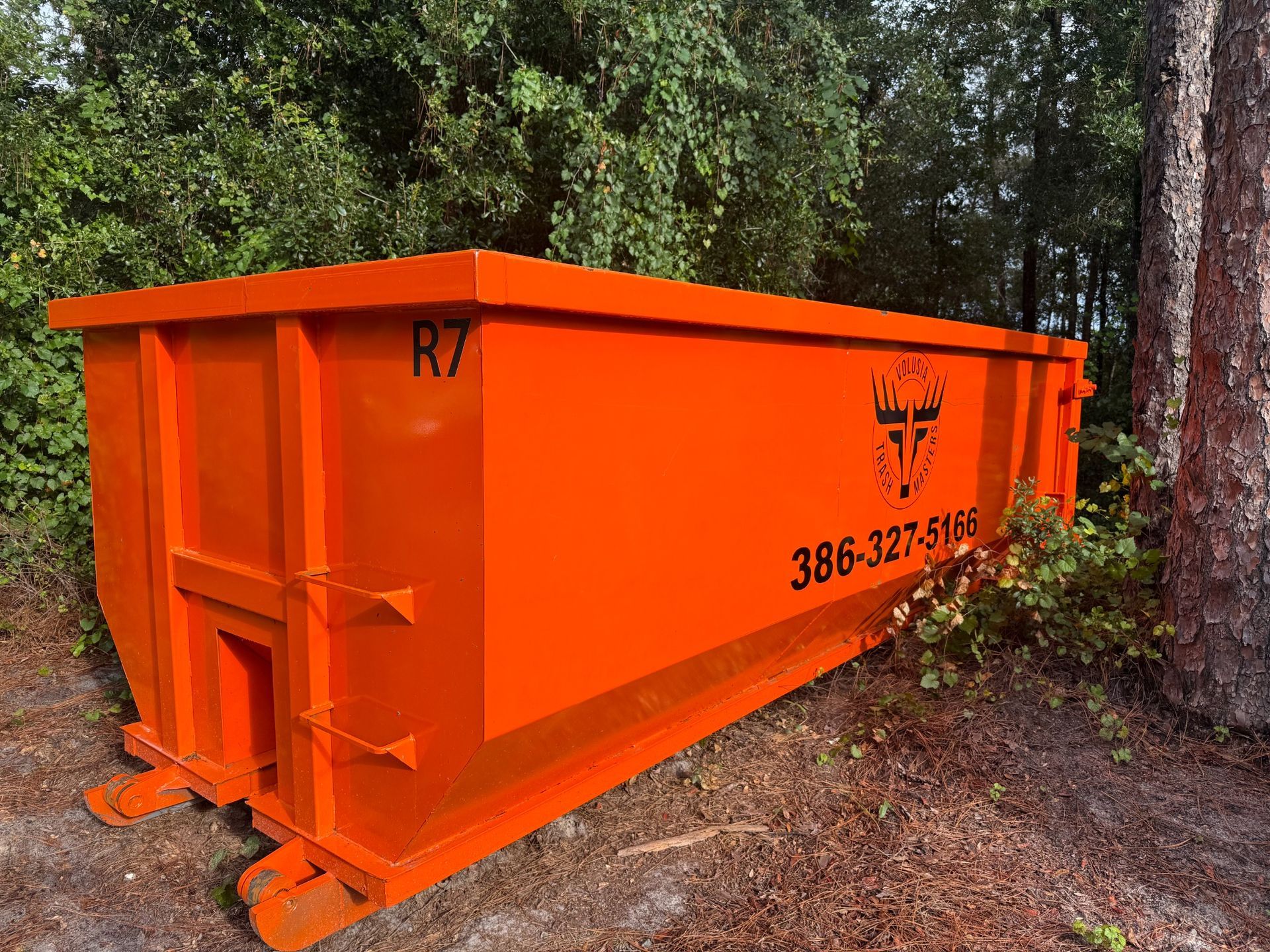 Orange Volusia Trash Masters roll-off dumpster for residential and construction cleanup in DeLand, Florida