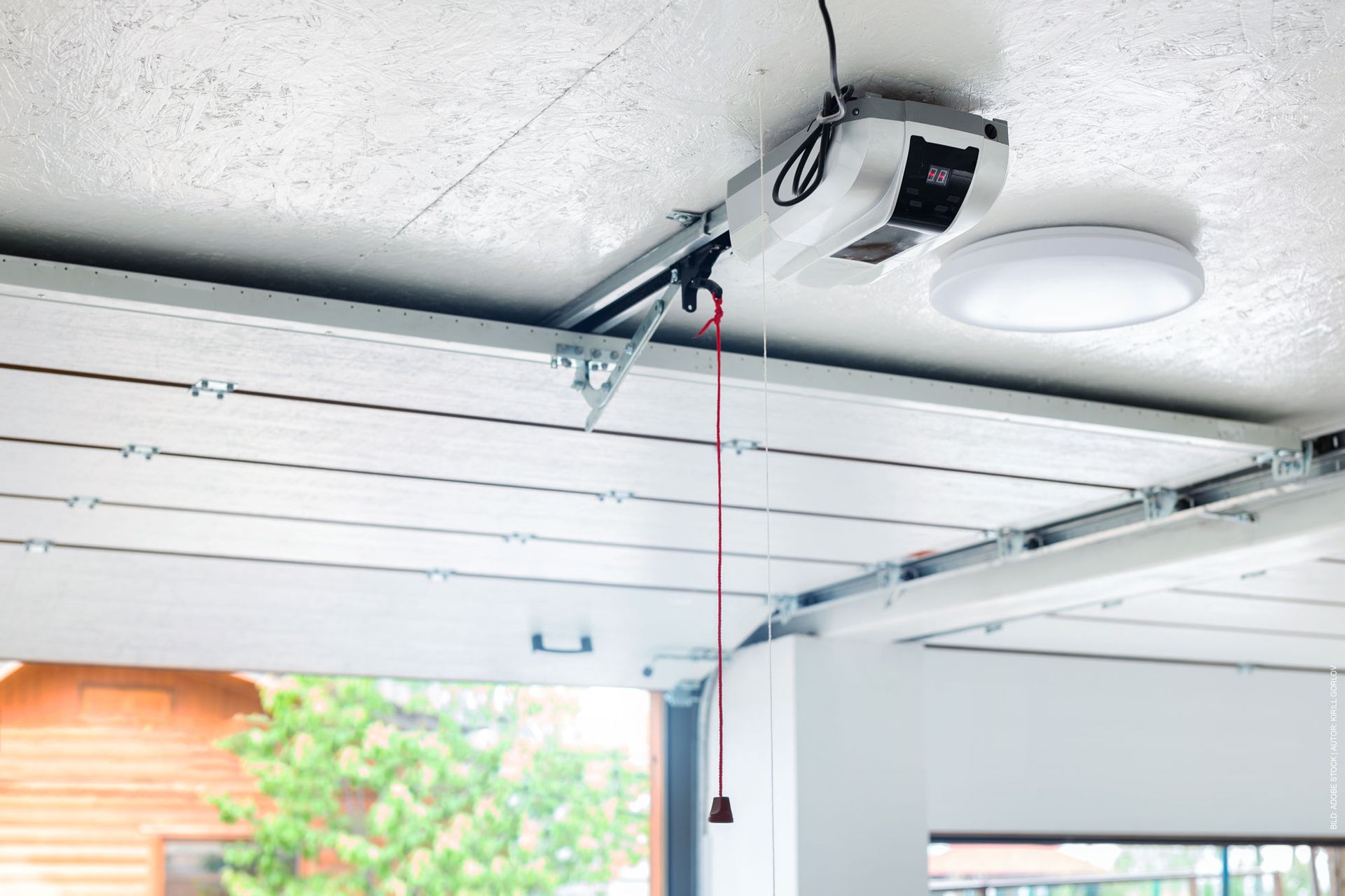 Ein Garagentoröffner hängt von der Decke einer Garage. Garagentor von Terrassenwelten Frank Merz