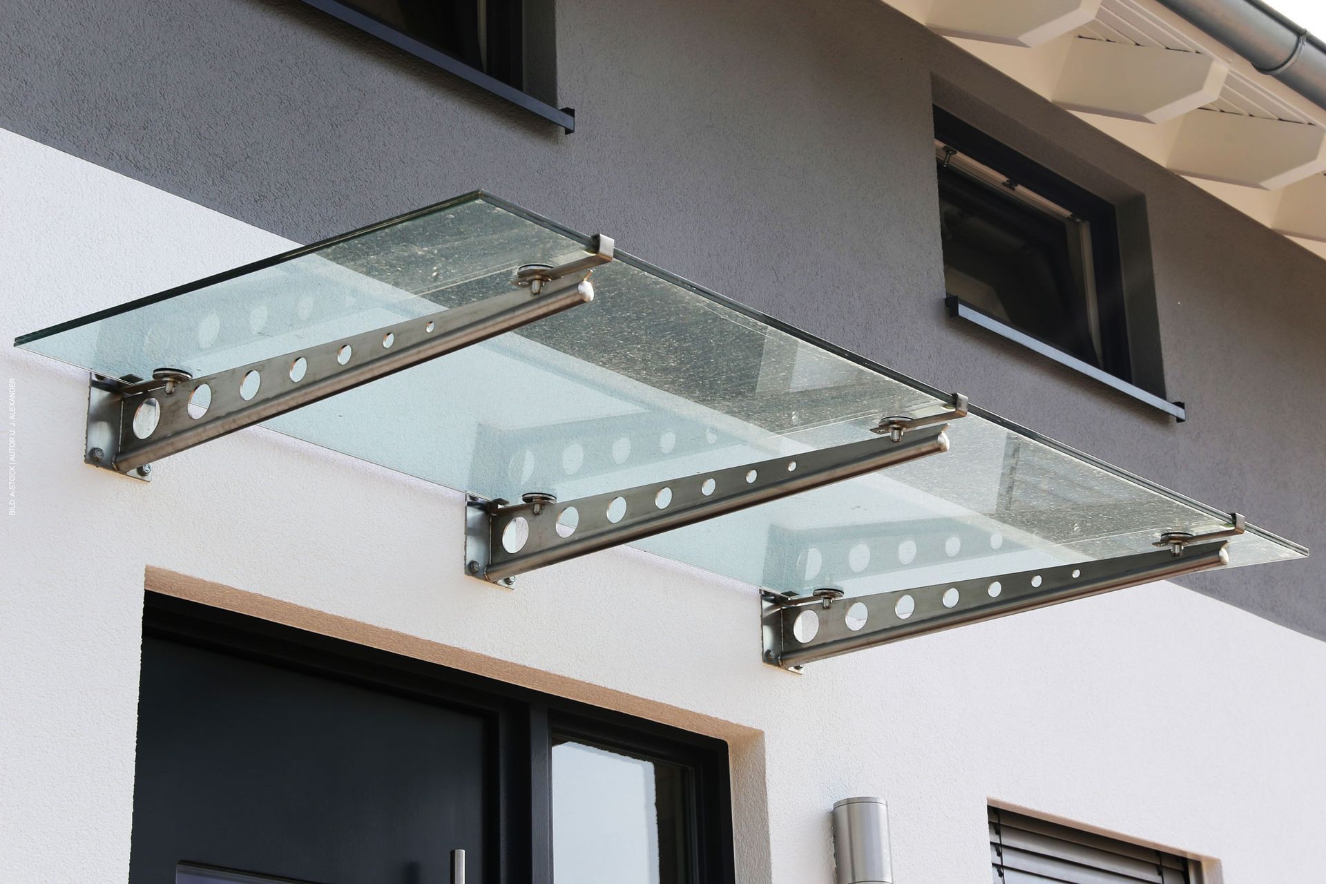 Ein modernes Haus mit einem Glasdach über der Tür. Haustürvordächer von Terrassenwelten Frank Merz