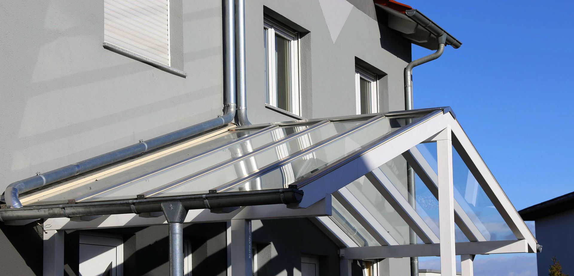 Ein Haus mit einem Vordach an der Vorderseite. Haustürvordächer von Terrassenwelten Frank Merz