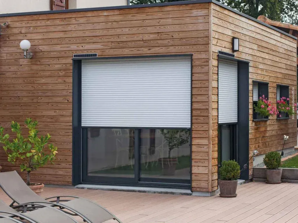 Ein Holzgebäude mit einem weißen Fensterladen. Bild von Bubendorff