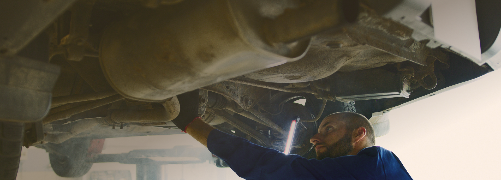 Mechanic inspecting the underside of a car on a lift in a garage | Len's Automotive