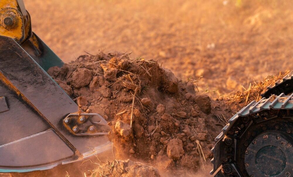 A Bulldozer Is Digging A Hole In The Dirt — Regional Concreting Solutions In Bathurst, NSW