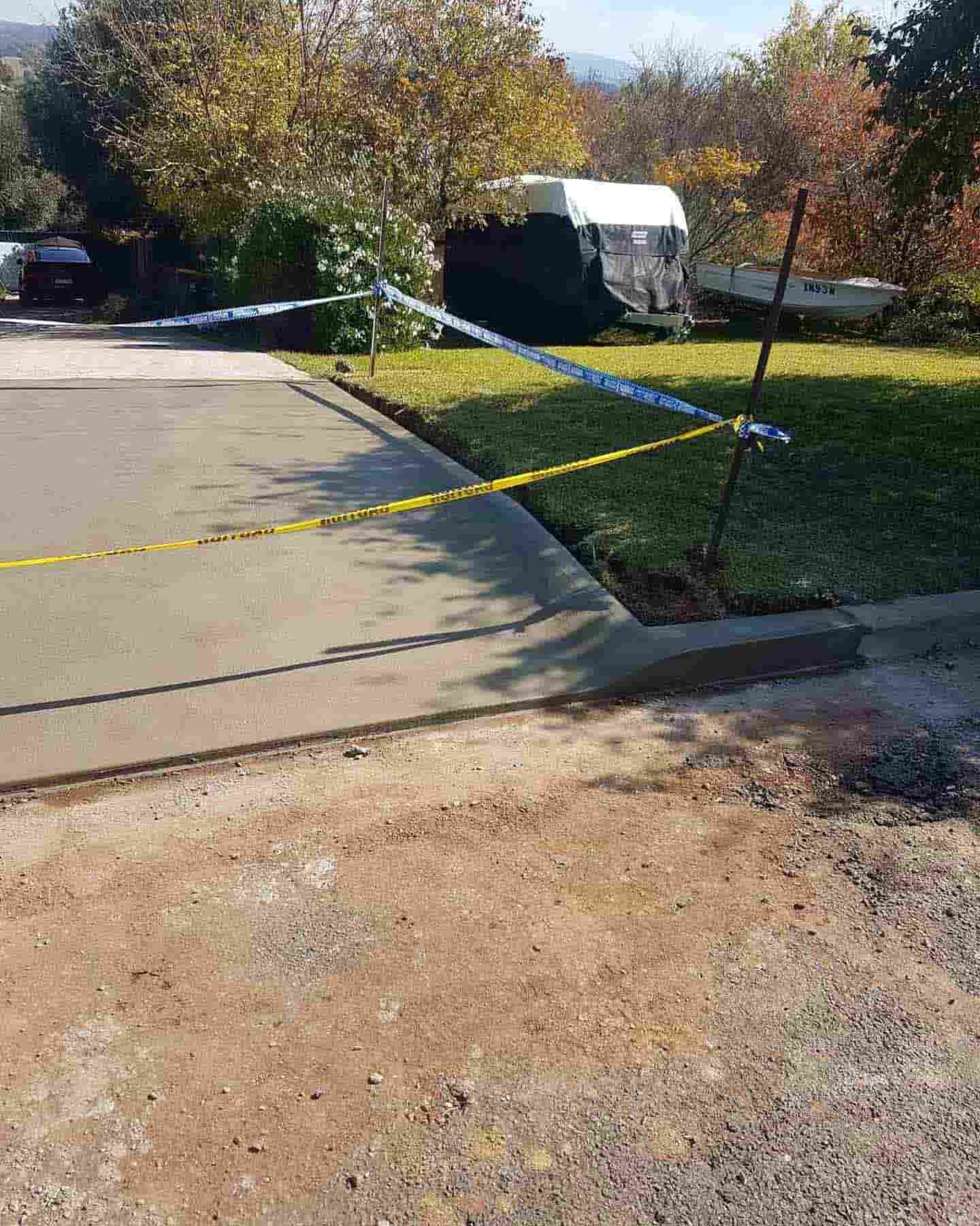 A Concrete Driveway With A Yellow Tape Covering It — Regional Concreting Solutions In Orange, NSW