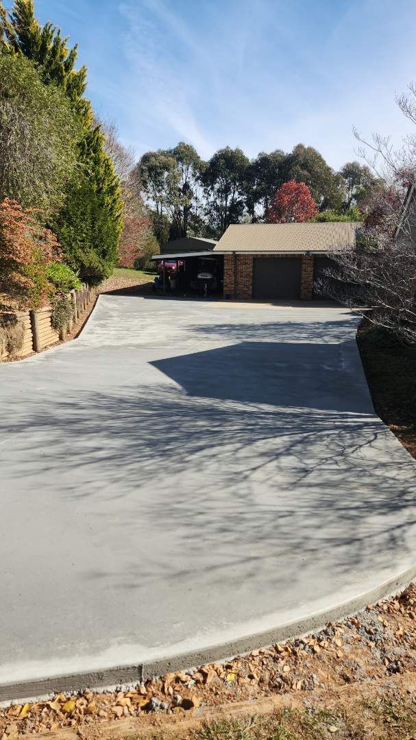 A Green Toy Truck Is Sitting On A Sidewalk Next To A Brick Building — Regional Concreting Solutions In Blayney, NSW