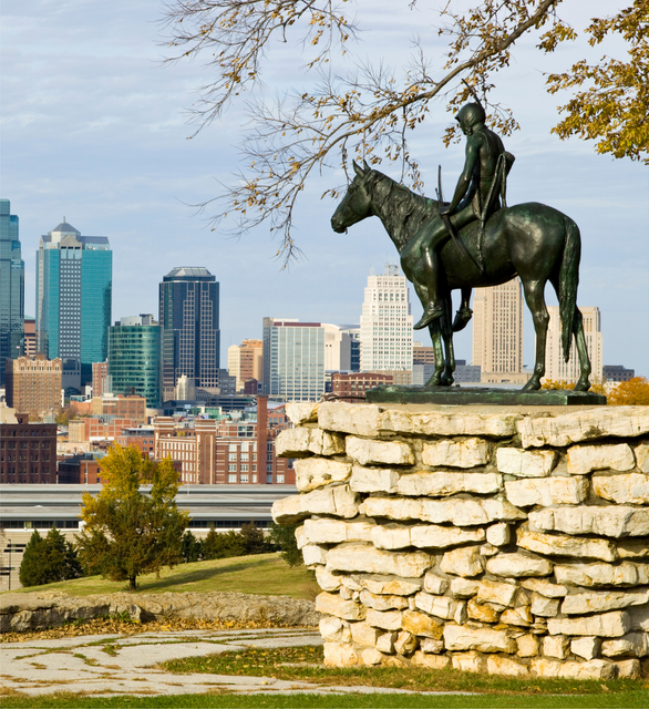 A bronze statue of a rider on a horse, set on a stone pedestal with the Kansas City skyline in the background. A bronze statue of a rider on a horse, set on a stone pedestal with the Kansas City skyline in the background.