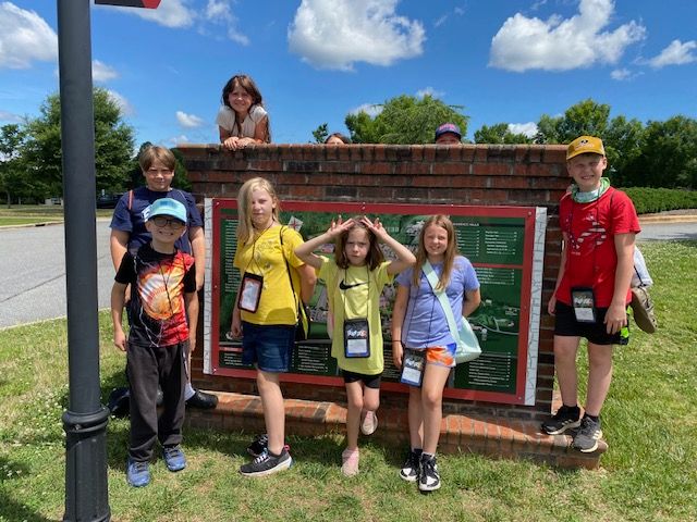 A group of children are posing for a picture in front of a sign.
