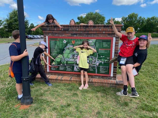 A group of children are posing for a picture in front of a sign.