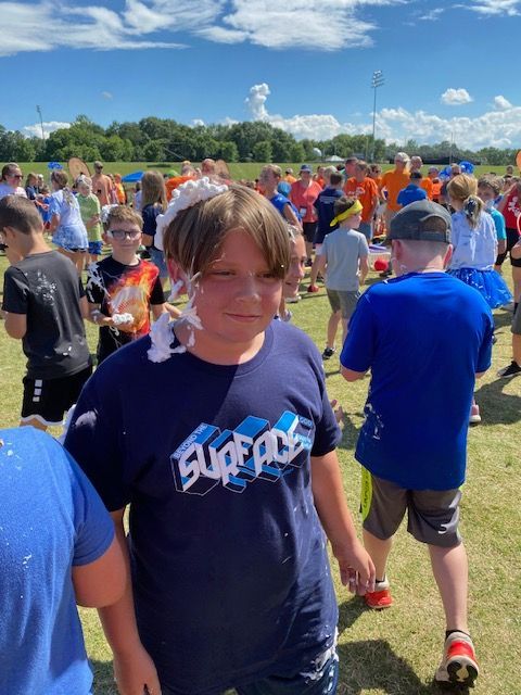 A boy with foam on his face is wearing a shirt that says super ace