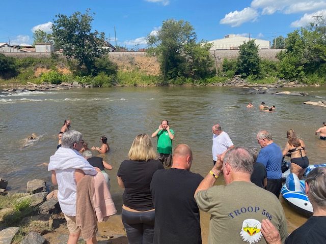 A group of people standing on the shore of a river