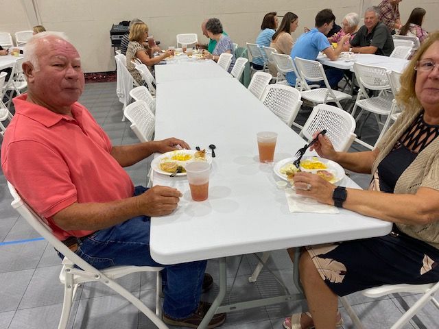 A man and a woman are sitting at a long table eating food.