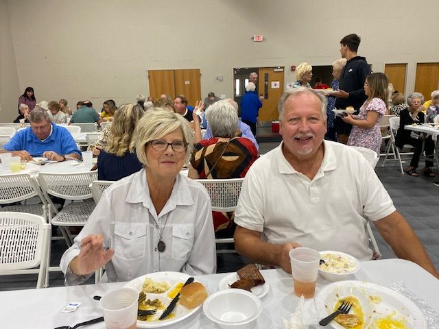 A man and a woman are sitting at a table with plates of food.