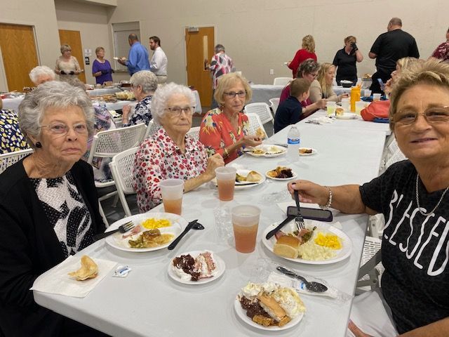 A group of older women are sitting at a table eating food.