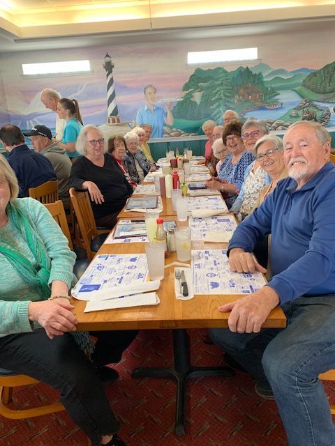 A group of people are sitting at long tables in a restaurant.