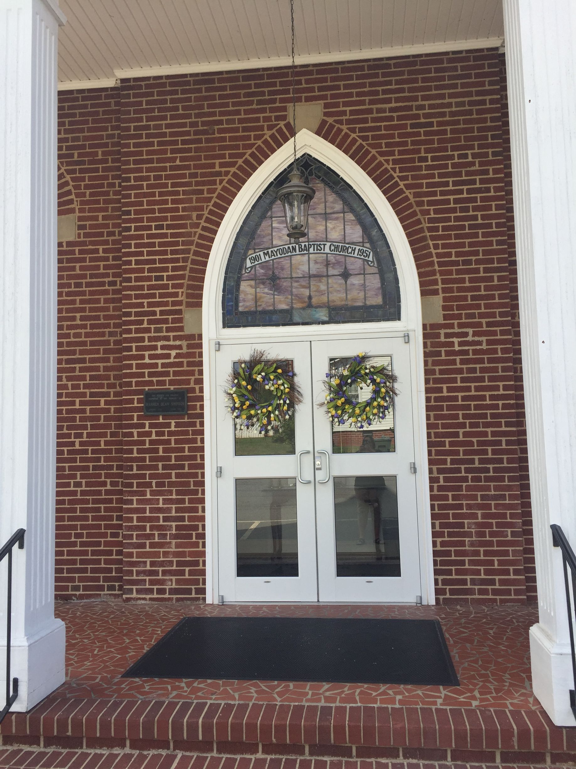 A brick building with a white door and a stained glass window
