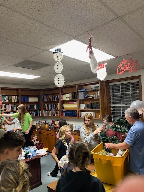 A group of people are gathered in a room decorated for christmas
