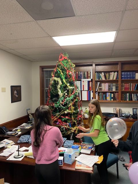 A group of people decorating a christmas tree in an office