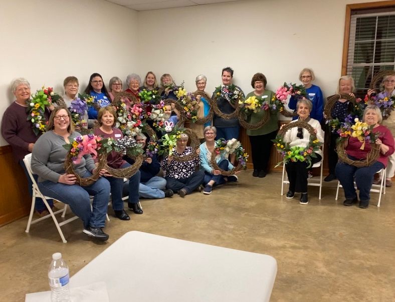 A group of women are holding wreaths in a room.