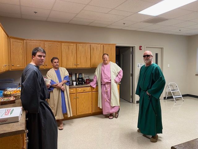 A group of men in robes are standing in a kitchen.
