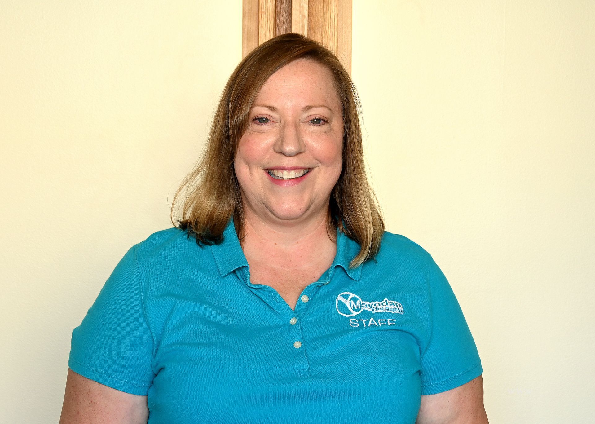 A woman in a blue shirt is smiling for the camera.