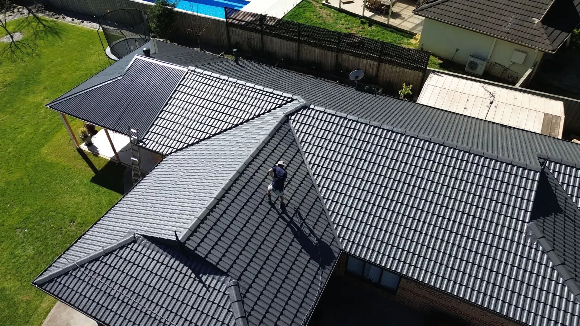 An aerial view of a roof of a house with a swimming pool in the background.
