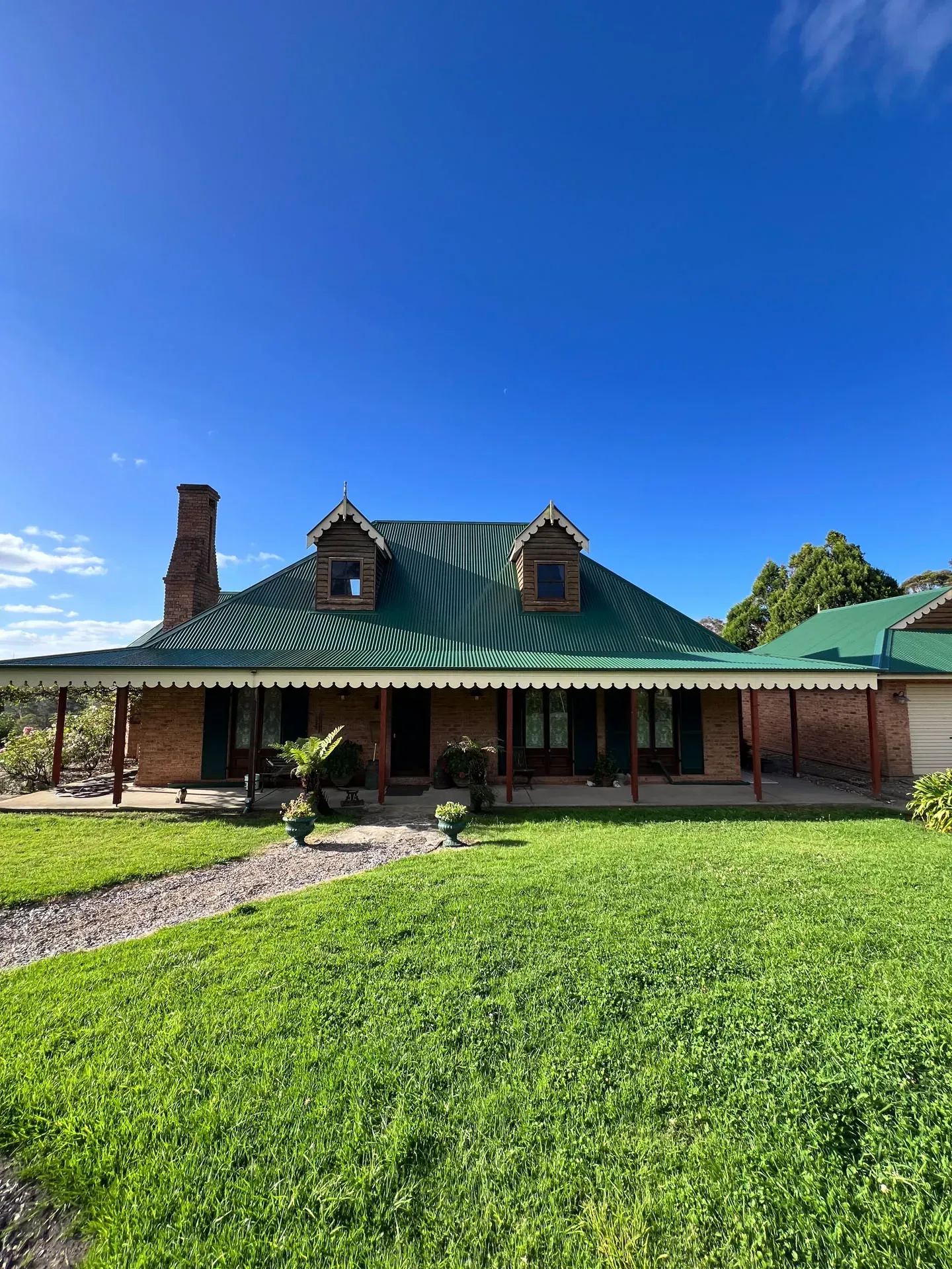 A large house with a green roof and a large lawn in front of it.