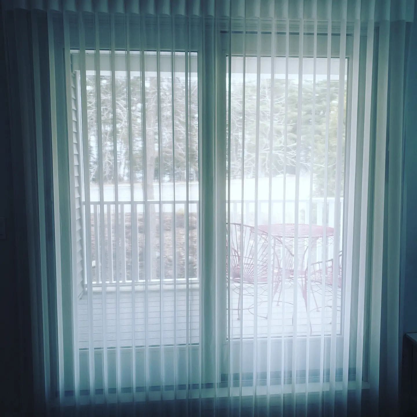 Sheer curtains over a bright window with a snowy outdoor balcony view