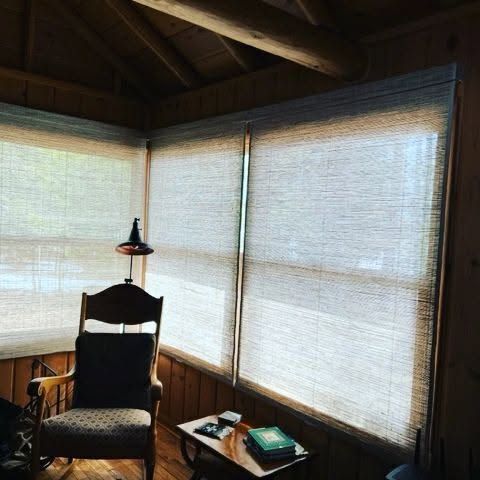 Wood-paneled room with large windows, a dark chair, and a small table by the corner.