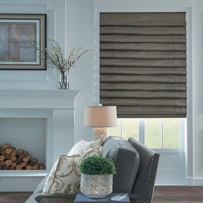 Cozy living room with gray chair, lamp, fireplace, and window with woven blind