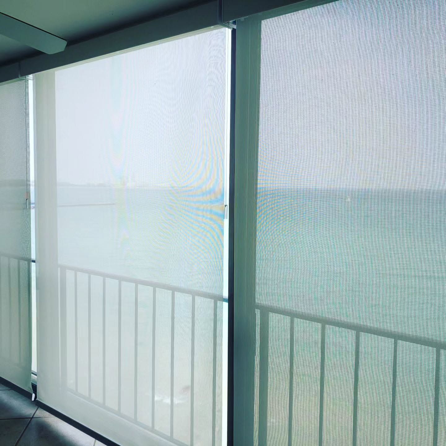 Sheer balcony curtains overlooking a bright waterfront view with railing